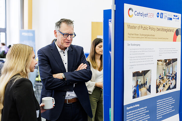 Catalyst GER Auftakt Info-Aufsteller 2 Die Teilnehmden betrachten eine Info-Wand beim Catalyst GER Auftakt