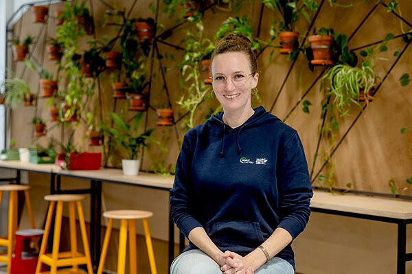 Gründungsberaterin Melusine Reimers vor einer Wand mit Pflanzen im Makerspace.