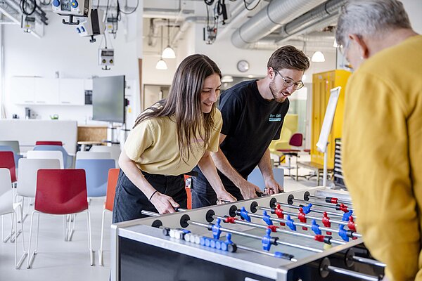 Drei Entrepreneure bei einem begeisterten Kicker-Spiel