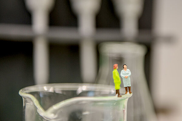 Zwei kleine Figuren auf dem Rand eines Reaktionsglas
