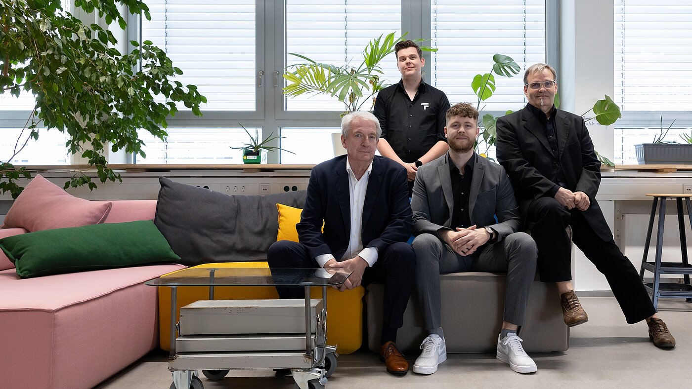 Das vierköpfige Team von TF-Industries sitzt auf einer Couch.