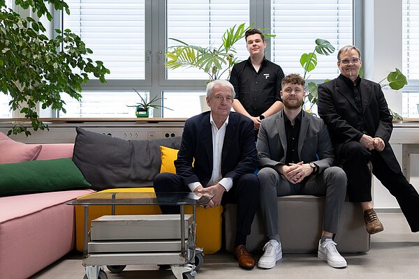 Das vierköpfige Team von TF-Industries sitzt auf einer Couch.