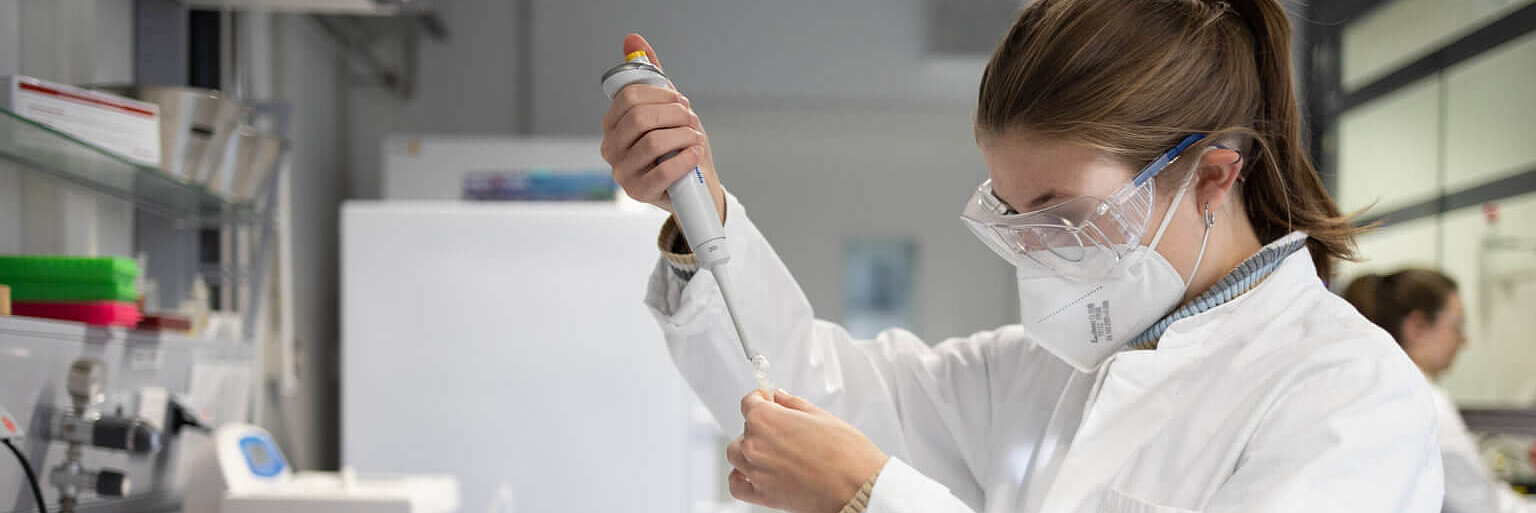Person im Labor füllt etwas in mit einer Pipette in ein Reagenzglas