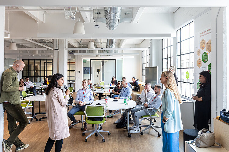 A female founder talkin into a microphone in front of a group of people.