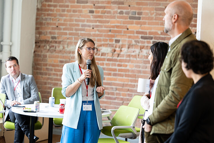 Start-up Coach Vanessa talks into a microphone in front of a group of entrepreneurs.