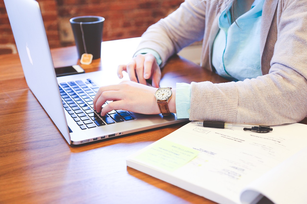 Legal Guide für Start-ups Mann schaut auf Laptop und macht sich handschriftliche Notizen.
